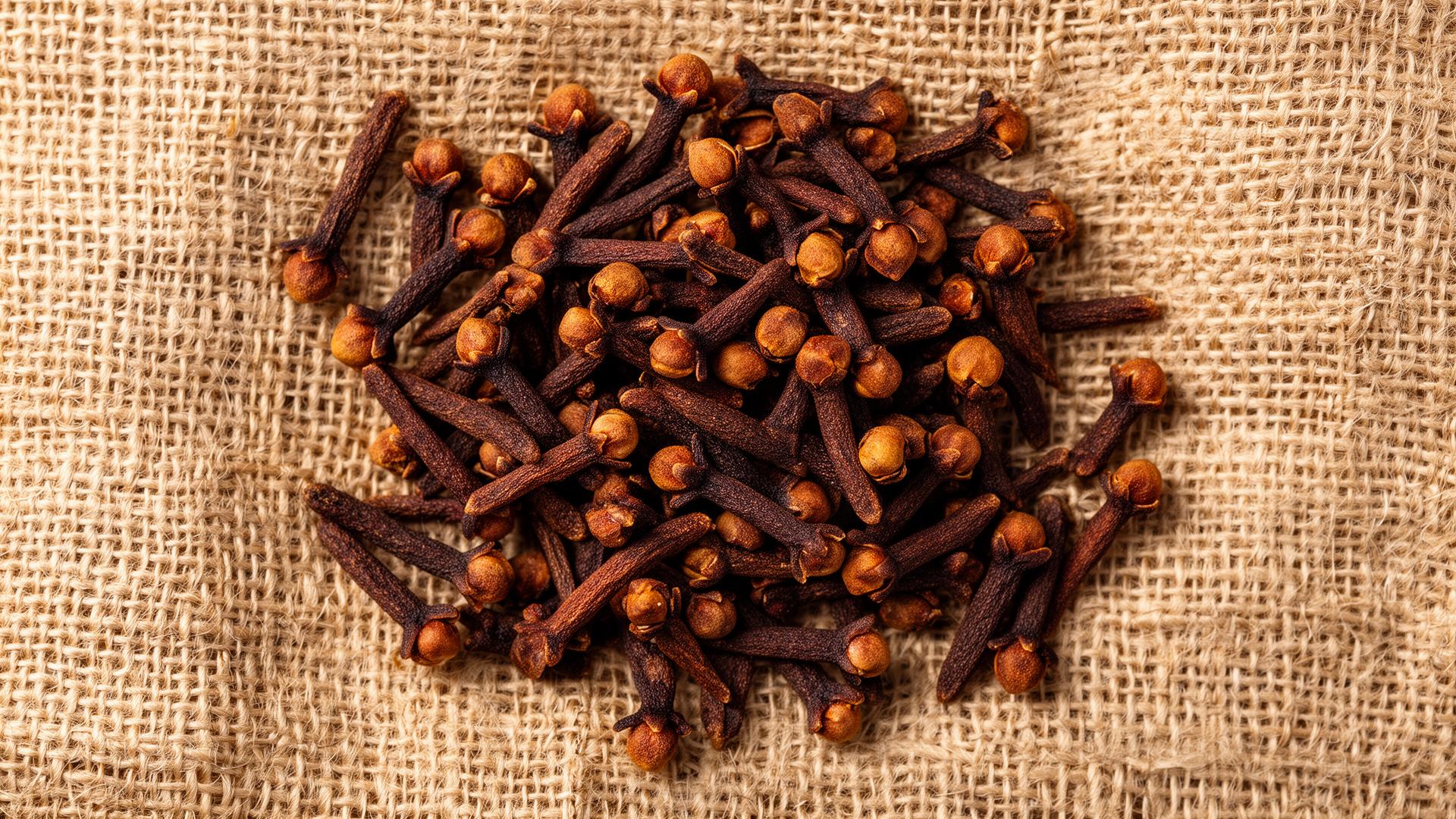 Whole dried cloves flat-lay on natural jute